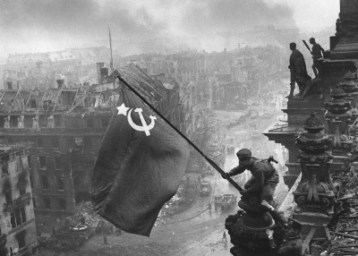 A Red Army soldier raises the Soviet Union flag over the Reichstag in Berlin, Germany, shortly before the official surrender of Nazi Germany in May 1945.