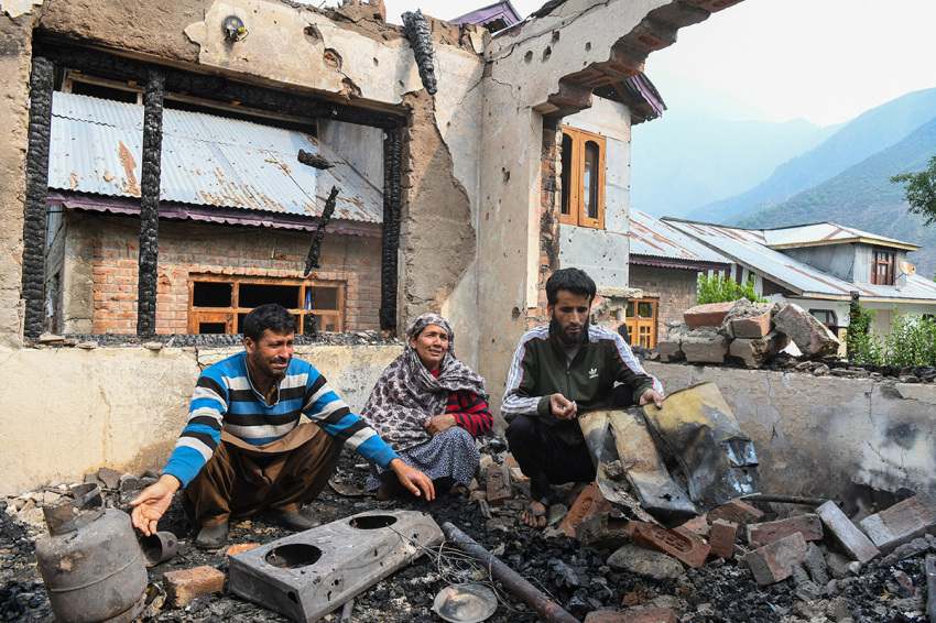 A family looks at the remains of their destroyed house following cross-border shelling between Pakistani and Indian forces in Salamabad uri village at the Line of Control (LoC).India's government said on May 8, 2025, that 13 civilians had been killed by Pakistani fire in