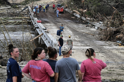 People look on as law enforcement and volunteers continue to search for missing people near Camp Mystic, the site of where at least 20 girls went missing after flash flooding in Hunt, Texas, on July 5, 2025. Rescuers were on Saturday searching for more than 20 girls missing from a riverside summer camp in Texas, after torrential rains caused devastating flooding that killed at least 27 people -- with more rain on the way. 