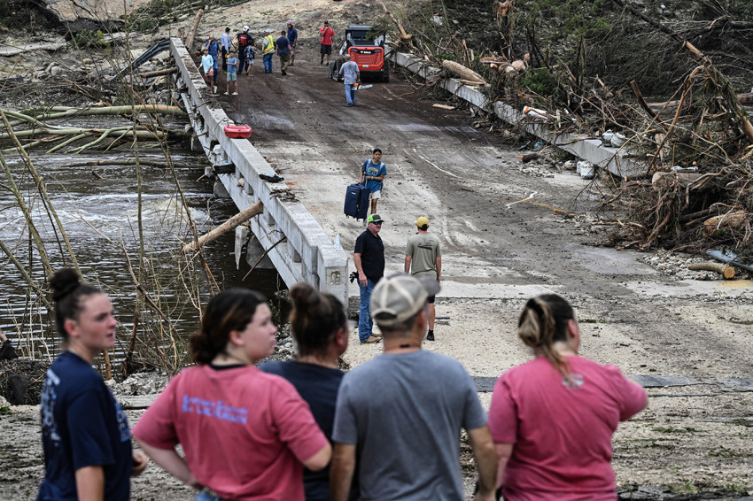 People look on as law enforcement and volunteers continue to search for missing people near Camp Mystic, the site of where at least 20 girls went missing after flash flooding in Hunt, Texas, on July 5, 2025. Rescuers were on Saturday searching for more than 20 girls missing from a riverside summer camp in Texas, after torrential rains caused devastating flooding that killed at least 27 people -- with more rain on the way. 