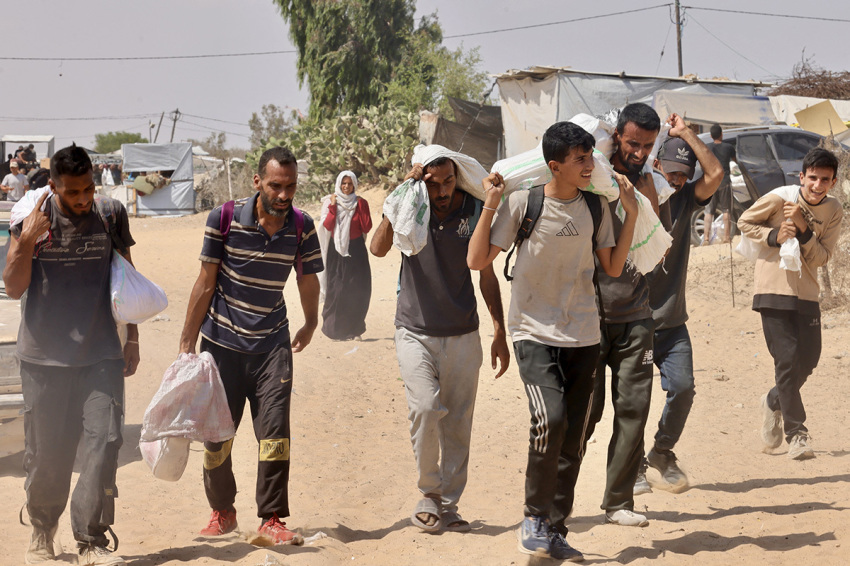 Palestinians carry humanitarian aid they received at the Rafah corridor as they walk in the Mawasi area of Rafah in the southern Gaza Strip on July 30, 2025.