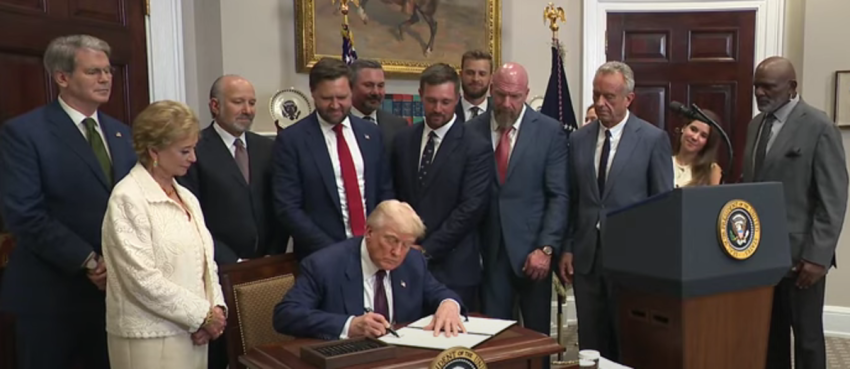 President Donald Trump signs an executive order restoring the Presidential Fitness Test as several administration officials and professional athletes look on, July 31, 2025. 