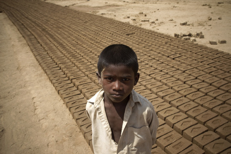 Pakistani child Shehrzad looks on beside formed clay bricks at a kiln on the outskirts of Rawalpindi on June 22, 2010. Human rights groups say kiln owners in Pakistan often dupe the poor into bonded labour by giving them loans, but in return are expected to work, often for little or no wages, in order to repay them. 