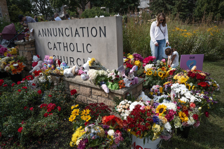 People visit a growing memorial outside of Annunciation Catholic Church on Aug. 29, 2025, in Minneapolis, Minnesota. On Aug. 27 a gunman fired through the stained-glass windows of the church while students were sitting in pews during a Catholic school Mass, killing two children and injuring at least 17 others. The gunman reportedly died at the scene from a self-inflicted gunshot wound, according to police. 
