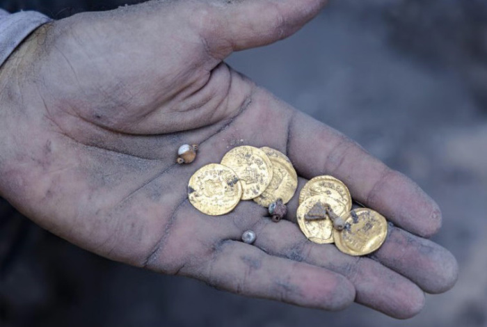 A handful of gold coins and pieces of jewelry as they were uncovered