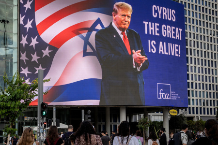 People walk underneath a billboard praising U.S President Donald Trump with the words 