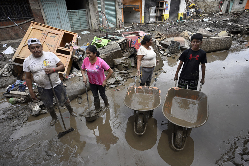 A family removes the mud after severe flooding hit the town of Huehuetla, Hidalgo state, Mexico, on Oct. 14, 2025. Rescuers scrambled on Oct. 13, 2025, to reach people cut off by devastating floods that have claimed 64 lives in central and eastern Mexico, with another 65 people reported missing. 