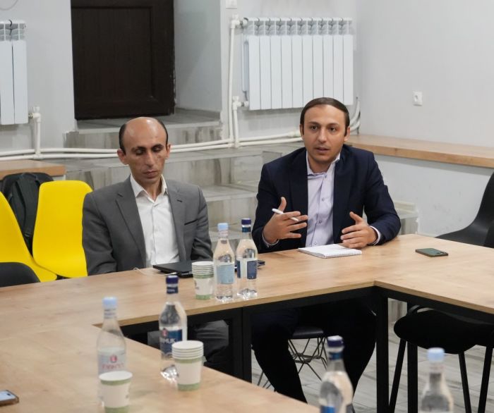 Gegham Stepanyan (right), the human rights ombudsman of Artsakh, speaks with a delegation of mostly American activists and journalists at a building in Yerevan, Armenia, that houses the government-in-exile of the Republic of Artsakh, on Sept. 24, 2025. He is flanked by Artak Beglarayan, a former state minister of Artsakh.