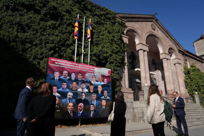 The delegation from Save Armenia looks at a sign showing the 23 Armenian hostages held by the Azerbaijan government in Baku outside of a building in Yerevan, Armenia, that houses the government-in-exile of the Republic of Artsakh, on Sept. 24, 2025.
