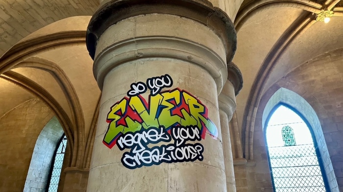 A graffiti from the "Hear Us" exhibit in Canterbury Cathedral in Canterbury, U.K., asks God, "Do you ever regret your creations?" The exhibit has drawn widespread criticism from figures such as Vice President J.D. Vance and Elon Musk.
