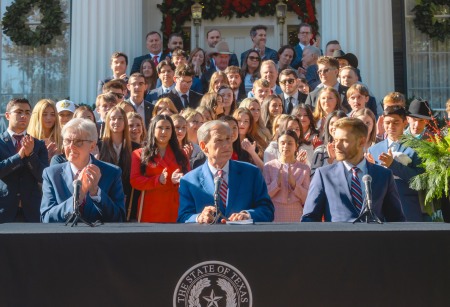 Texas Gov. Greg Abbott (center) is joined by  Lt. Gov. Dan Patrick and Texas Education Agency (TEA) Commissioner Mike Morath along with TPUSA supporters at the Governor's Mansion in Austin, Texas on Dec. 8, 2025.