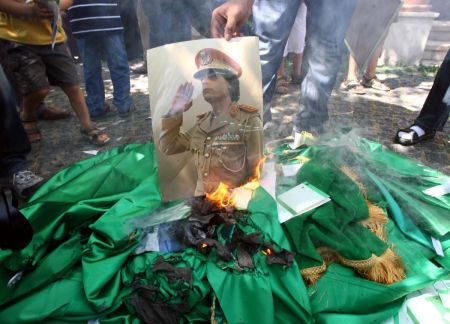 Demonstrators set fire to a poster of Libyan leader Muammar Gaddafi, copies of his book and Libyan flags during a protest against Kadhafi outside the Libyan embassy in Ankara on August 22, 2011. 