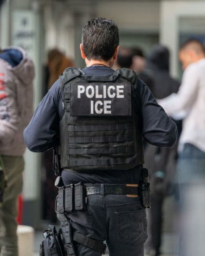 An ICE agent monitors hundreds of asylum seekers being processed upon entering the Jacob K. Javits Federal Building on June 6, 2023 in New York City. New York City has provided sanctuary to over 46,000 asylum seekers since 2013, when the city passed a law prohibiting city agencies from cooperating with federal immigration enforcement agencies unless there is a warrant for the person's arrest.