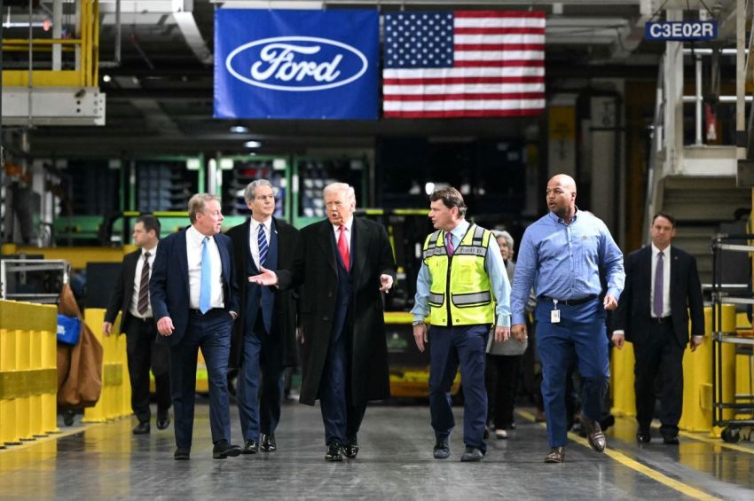 President Donald Trump speaks with Ford Executive Chairman Bill Ford (L), Treasury Secretary Scott Bessent, Ford CEO Jim Farley (2nd R), and plant manager Corey Williams (R) as he tours Ford Motor Company's River Rouge complex in Dearborn, Michigan, on January 13, 2026.