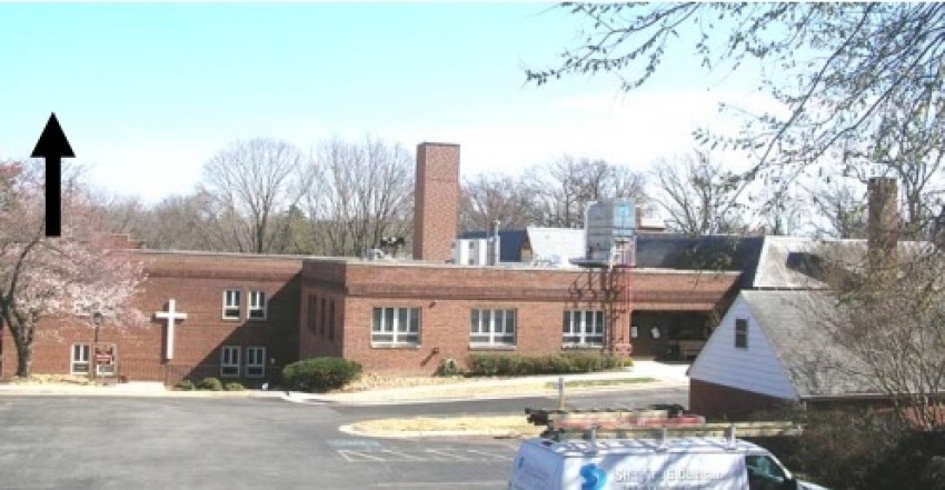 A view of St. Luke Lutheran Church from the parking area off of Dale Drive in Silver Spring, Maryland. The approximate location and height of the AT&T faux chimney proposed in an October 2013 application is indicated by the arrow on the left. The T-Mobile chimney is located in the center of the photo. The real chimney originally constructed at the church is visible on the right. 