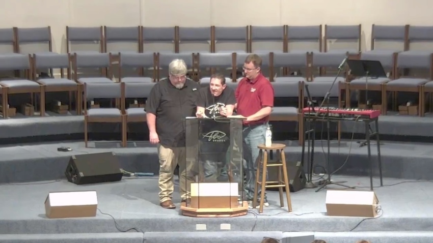 Pastor Matt Olson is physically upheld at the point of his exhaustion while preaching the sufficiency of Christ's righteousness from the book of Romans on June 2, 2026.