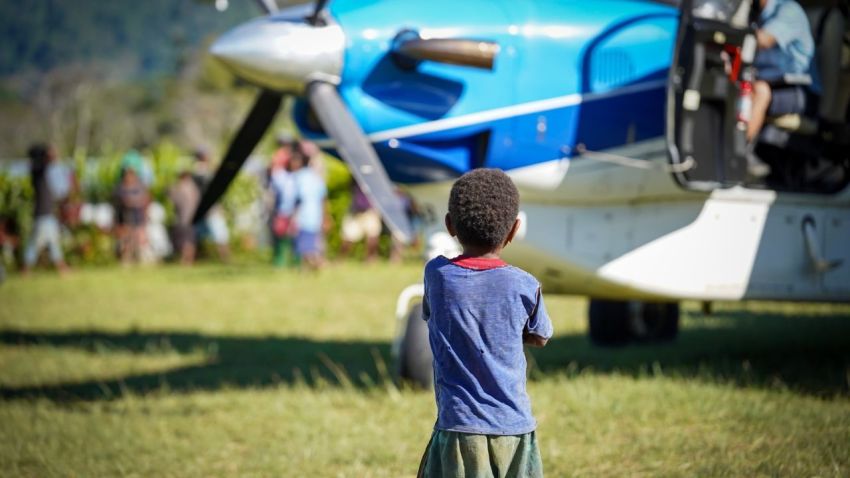 A child stands in front of a JAARS plane.
