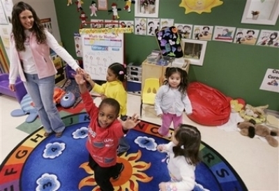 In this Feb. 28, 2006, file photo, three-year-old Nathan Austin, center, dances around his classroom with teacher Jennifer Grillo-Bates, left, and classmates at the Egenolf Early Childhood Center in Elizabeth, N.J. According to a new study by the National Institutes of Health, youngsters who had quality child care before kindergarten had better vocabulary scores by fifth grade, but the more time they spent in child care, the more likely their sixth grade teachers were to report problem behaviors. 