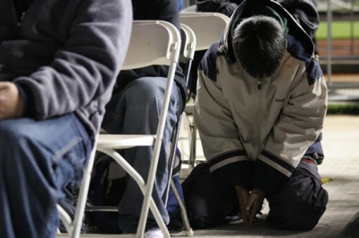 A teen gets down in prayer during Teen Mania's BattleCry 2007 at San Francisco's AT&T Park.
