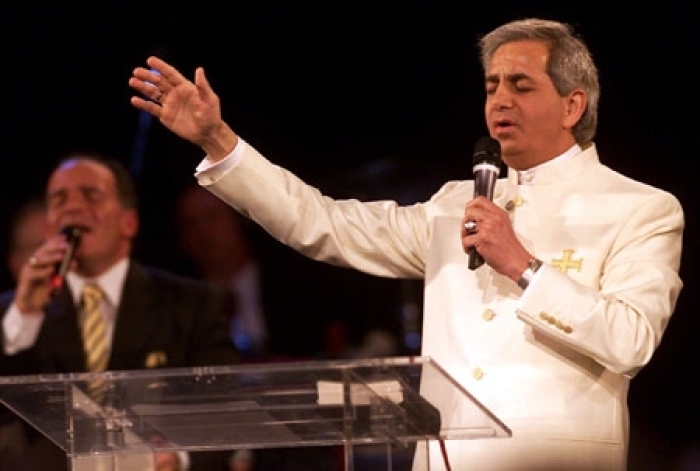 Benny Hinn prays during a service at the Blaisdell Concert Hall in Honolulu on Jan. 11, 2002. His crusades around the world draw thousands who hope the diminutive minister will zap them with power absorbed from the graves of dead faith healers.