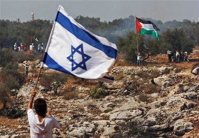 In this file photo, a man holds an Israeli flag as another holds a Palestinian flag.