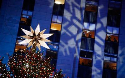 People look on from office windows as the Rockefeller Center Christmas tree stands lit during the 76th annual lighting ceremony Wednesday, Dec. 3, 2008, in New York.