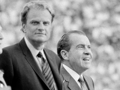 Evangelist Billy Graham, center, and President Richard Nixon, right, survey the capacity crowd of more than 65,000 attending Graham's Crusade at Neyland Stadium on the campus of the University of Tennessee, May 28, 1970. At left is first lady Pat Nixon.