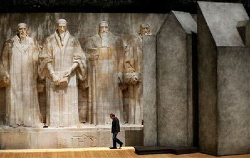 In this June 10, 2009 photo, a worker passes by the Reformation Wall with statues of William Farel, John Calvin, and John Knox, from left to right, in the grounds of the university in the center of Geneva, Switzerland. Preparations started to commemorate the 500th anniversary of John Calvin's birth on July 10, 1509. Calvin was a principal figure in the development of the system of Christian theology later called Calvinism.