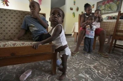 A toddler orphaned in the recent earthquake props himself against a couch as he practices walking, inside one of several dozen homes for orphans at SOS Children's Village, outside Port-au-Prince, Wednesday, April 14, 2010.