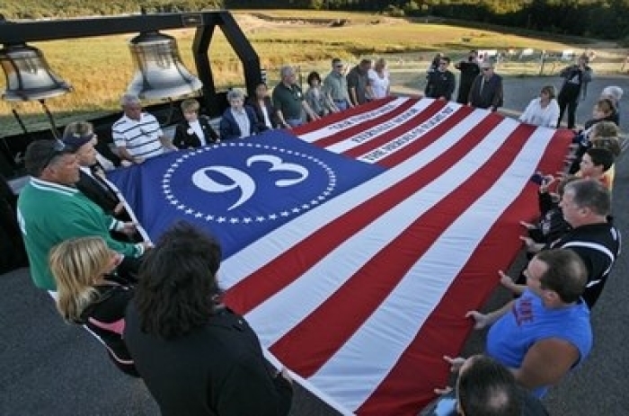 Visitors to the temporary Flight 93 memorial in Shanksville, Pa., participate in a sunset memorial service on Friday, Sept 10, 2010 Friday, Sept. 10, 2010. The crash site of Flight 93 and the construction of the permanent memorial can be seen in the field in the top center of the background.