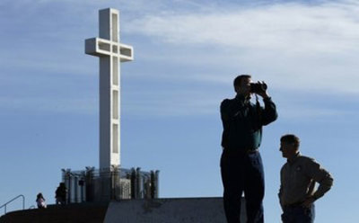 Rev. John Fredericksen of Orlando, Fla., takes a picture in front of the war memorial cross on Mount Soledad Tuesday, Jan. 4, 2011, in San Diego, alongside Burdette Streeter of San Diego.