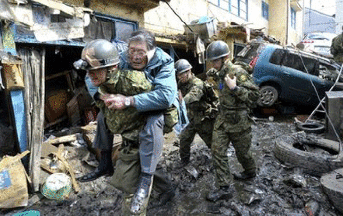 A man who's been stranded in a residence is carried on the back of a Japanese soldier to higher grounds at Kesennuma, northeastern Japan, on Saturday March 12, 2011, one day after a giant quake and tsunami struck the country's northeastern coast.