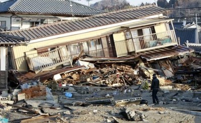 A residents of the seaside town of Yotsukura, northern Japan, walks past damaged homes Monday, March 14, 2011, three days after a giant quake and tsunami struck the country's northeastern coast.