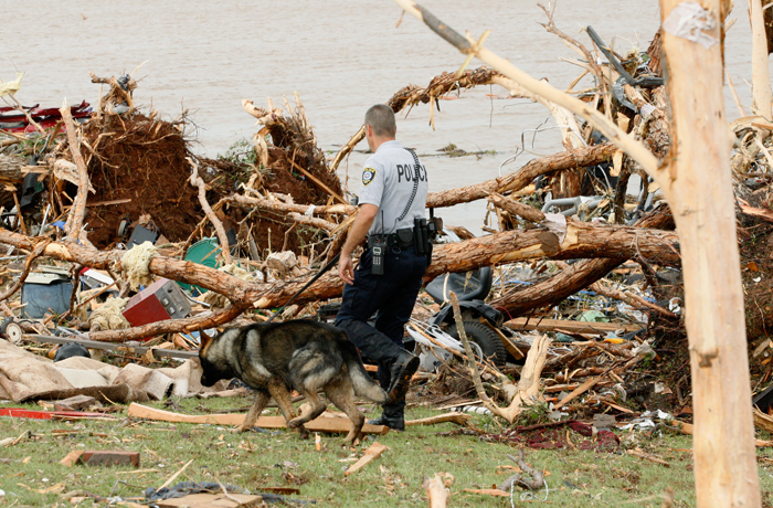A police officer uses a K-9 partner dog to search for a missing child near the lake shore after a tornado ripped through the Falcon Lake area of Piedmont, Oklahoma May 24, 2011.