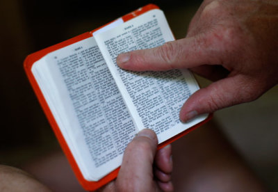 In this file photo, a man reads a pocket Bible at the Creation Christian music festival near Mount Union, Pennsylvania, June 29, 2008.