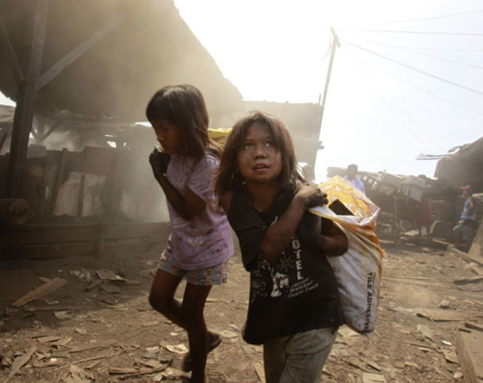 Girls carry sacks in a charcoal factory at a slum in Manila April 12, 2011.