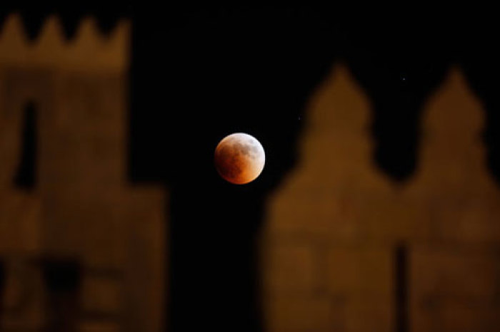 The moon is seen behind the wall of Damascus gate in Jerusalem Old City during a total lunar eclipse June 15, 2011.