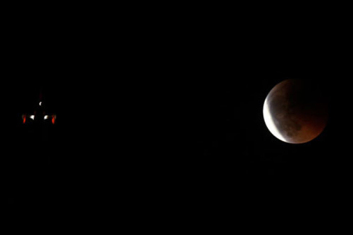 An aircraft flies as the shadow of the earth falls on the moon during a total lunar eclipse in Malaga, southern Spain, late June 15, 2011.