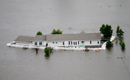A home is seen submerged in flood waters from the Souris River, after sand bags failed to hold the water back in Minot, North Dakota June 24, 2011. Federal officials sharply increased plans to release more water on the swollen Souris River on Thursday, adding up to three feet to the expected peak of flooding at Minot, North Dakota, where thousands of homes already have been evacuated.