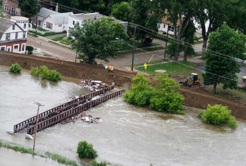 Workers inspect a flooded pedestrian walk way, as debris is trapped by the structure in Minot, North Dakota, June 24, 2011. Federal officials sharply increased plans to release more water on the swollen Souris River on Thursday, adding up to three feet to the expected peak of flooding at Minot, North Dakota, where thousands of homes already have been evacuated.