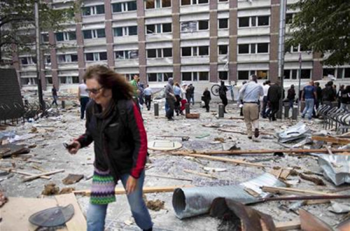 People walk through debris after a powerful explosion rocked central Oslo, July 22, 2011.