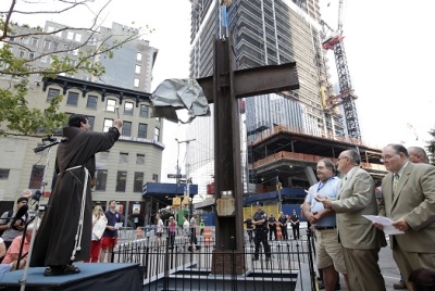 Father Brian Jordan (L), a Franciscan Priest, blesses The World Trade Center Cross, made of intersecting steel beams found in the rubble of buildings destroyed in the September 11 2001 attacks on the World Trade Center, before it is transported and lowered by a crane into an opening in the World Trade Center site below ground level where it will become part of the permanent installation exhibit in the 9/11 Memorial and Museum, in New York, July 23, 2011.