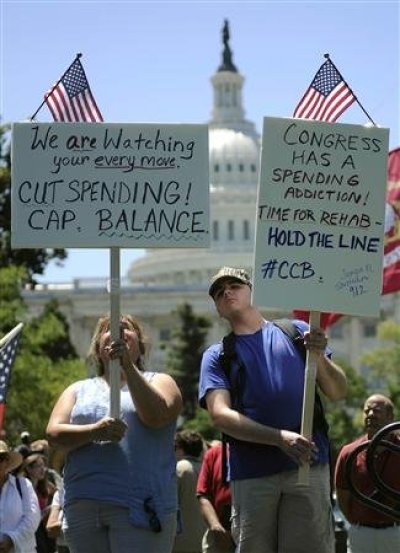 Dozens of Tea Party supporters carry signs as they rally near the U.S. Capitol against raising the debt limit in Washington, July 27, 2011.