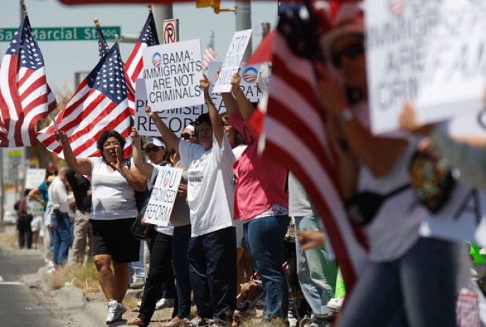 People wave U.S. flags and hold signs at a protest against immigration laws during a visit of President Barack Obama to El Paso May 10, 2011.