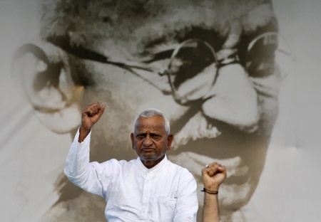 Veteran Indian social activist Anna Hazare raises his fist in front of a portrait of Mahatma Gandhi at Ramlila grounds in New Delhi August 19, 2011.