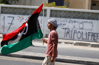 A Libyan rebel fighter carries the Kingdom of Libya flag in Tripoli August 23, 2011.