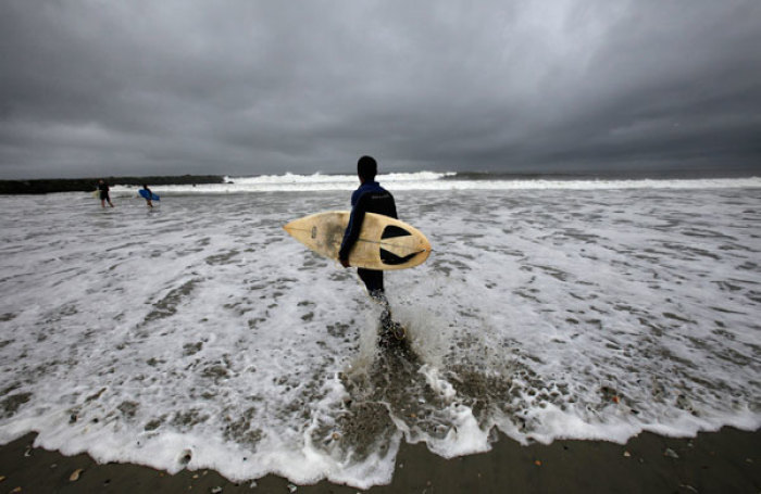 A surfer walks into the water ahead of Hurricane Irene's arrival, on Rockaway Beach in New York August 27, 2011. Mayor Michael Bloomberg sternly warned New Yorkers to follow the city's unprecedented mandatory evacuation orders on Saturday, saying approaching Hurricane Irene is 'life-threatening' and 'not a joke.' Some 370,000 of the city's more than 8 million residents are under orders to leave their homes in low-lying and waterfront areas, largely in the boroughs of Brooklyn and Queens and in the financial district in downtown Manhattan.