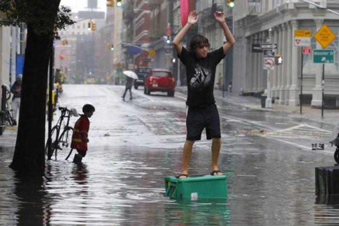 A boy stands on a newspaper box in a flooded street in the Soho section of Manhattan after Hurricane Irene passed over the New York City area August 28, 2011. Hurricane Irene battered New York with heavy winds and driving rain on Sunday, knocking out power and flooding some of Lower Manhattan's deserted streets even as it lost some of its strength. Irene was downgraded to a tropical storm on Sunday morning but was still sending waves crashing onto shorelines and flooding coastal suburbs.