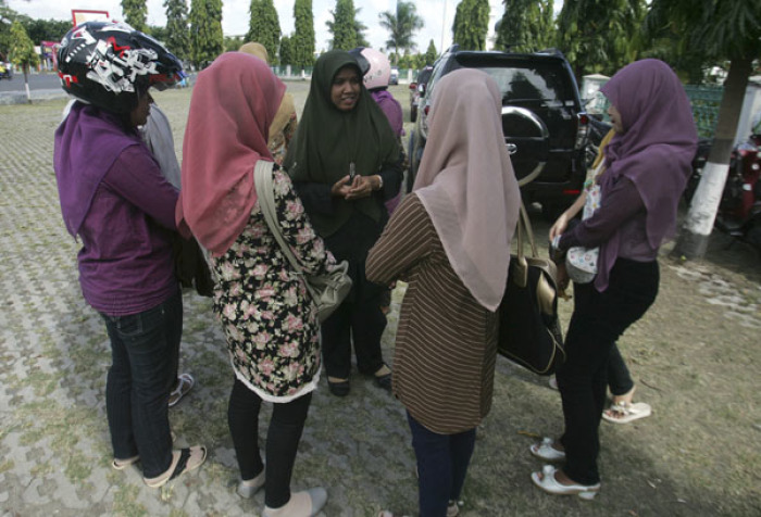 A Sharia policewoman (C) speaks to women caught flouting an Indonesian province's dress code by wearing tight jeans and pants, during a street inspection in Banda Aceh June 9, 2011.