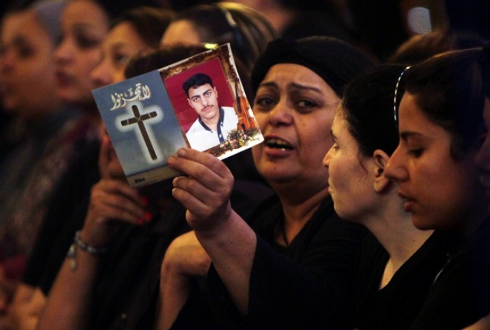 An Egyptian Christian woman grieves and show a picture of her son during a mass funeral for victims of sectarian clashes with soldiers and riot police at a protest against an attack on a church in southern Egypt at Abassaiya Cathedral in Cairo.